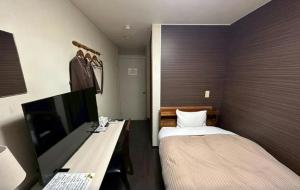 a bedroom with a bed and a desk with a computer at 水戸第一ホテル本館 in Mito