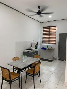 a table and chairs in a kitchen with a ceiling fan at PL Homestay 2 in Padang Lembu