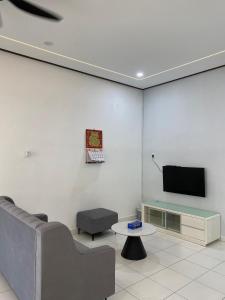 a living room with a couch and a tv on a wall at PL Homestay 2 in Padang Lembu