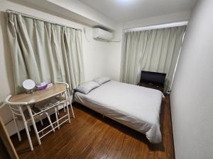 a small bedroom with a bed and a desk and a window at Namba Ebisu Tower701 in Osaka