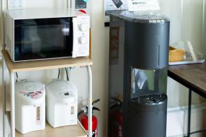 a coffee maker and a microwave on a shelf at ペンションレークサイド in Otsu