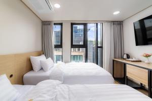 two beds in a hotel room with a window at Bliss Hotel Myeongdong in Seoul