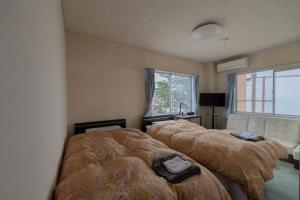 a bedroom with two beds and a window at ペンションレークサイド in Otsu
