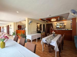 a dining room with tables and chairs and a kitchen at Rufana Suites in Moalboal