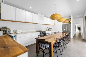 a kitchen with white cabinets and a wooden table and chairs at Barra Luxe Beach House 4BR Yaroomba Beach Stay in Yaroomba