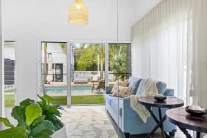 a living room with a blue couch and two tables at Barra Luxe Beach House 4BR Yaroomba Beach Stay in Yaroomba +25 photos