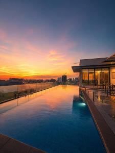 a building with a pool with a sunset in the background at Opulent Nights Sky Hotel 2BR Family Stay KK in Kota Kinabalu