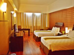 Habitación de hotel con 2 camas y TV en Grand Elite Hotel Pekanbaru, en Pekanbaru