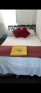 a bed with a yellow blanket and red pillows on it at Guest house in Basseterre