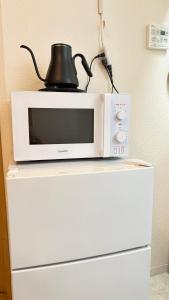 a microwave sitting on top of a white refrigerator at Ueno Sakura Inn 上野公园 in Tokyo