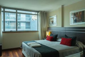 a bedroom with a bed with red pillows and a window at Zoom Apartments Hotel in Córdoba