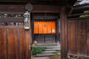 an entrance to a wooden gate with an orange door at 丹徳庭園 in Kawagoe +5 photos