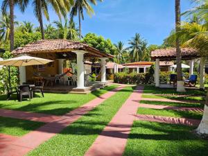 a garden with a walkway and chairs and palm trees at Enjoy Cabo del Sol Costa del Sol in El Zapote