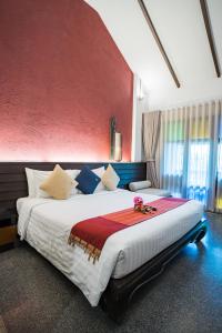 a bedroom with a large bed with a red wall at De Lanna Hotel in Chiang Mai +82 photos