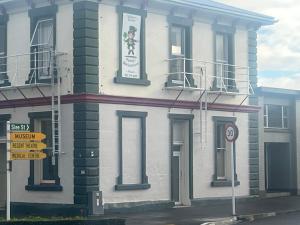 a white building with a sign on the side of it at Sullivans backpackers in Waimate