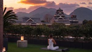 a woman sitting in a yoga position with a candle at Kumamoto Hotel Castle in Kumamoto +173 photos
