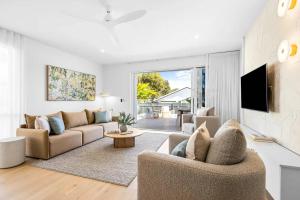 a living room with two couches and a tv at Key West Beach House in Coolum Beach