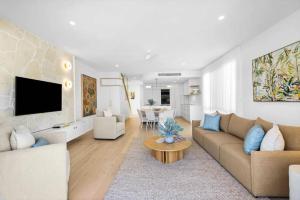 a living room with a couch and a tv and a table at Key West Beach House in Coolum Beach