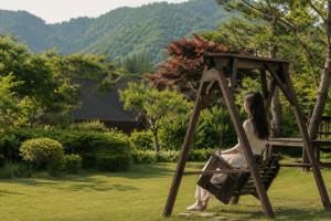 a woman sitting on a swing in the grass at Pyeongchang Estrella Pension in Pyeongchang