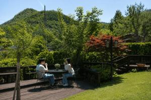 two people sitting at a table in a garden at Pyeongchang Estrella Pension in Pyeongchang