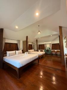 two beds in a large room with wooden floors at เพลินนะเพลินนา รีสอร์ต Ploennaploenna in Ban Rim Lao