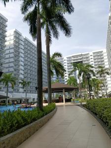 a walkway with palm trees in front of a building at Shell Residences MOA Elegant Place in Manila