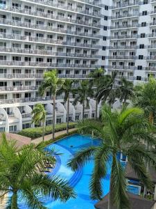 a large apartment building with a blue pool and palm trees at Shell Residences MOA Elegant Place in Manila