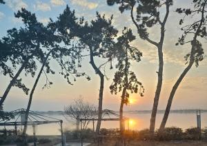 a sunset over a body of water with trees at Muan Topmeori Pension in Muan