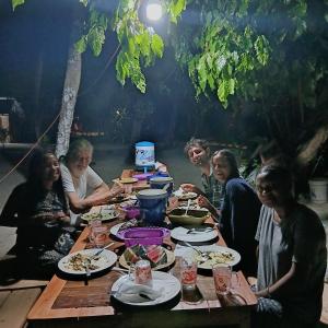 a group of people sitting around a table eating food at Isiie Homestay in Merpati