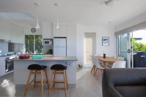 a kitchen and living room with a counter and stools at Villa Pandanus in Peregian Beach +18 photos
