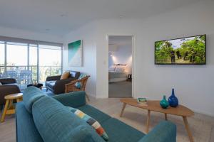 a living room with a blue couch and a table at Villa Pandanus in Peregian Beach