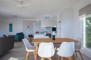 a kitchen and living room with a wooden table and white chairs at Villa Pandanus in Peregian Beach