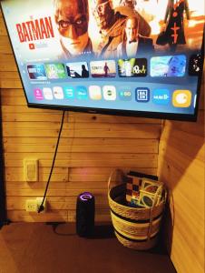 a flat screen tv hanging on a wall with a basket at Glamping villeta campo heliconias in Villeta