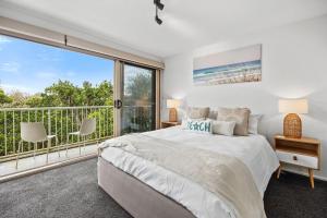a bedroom with a bed and a large window at Peregian Beach Apartment in Peregian Beach +14 photos