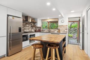 a kitchen with a wooden table and stainless steel appliances at Peregian Beach Apartment in Peregian Beach