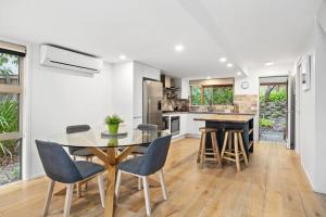 a kitchen and dining room with a glass table and chairs at Peregian Beach Apartment in Peregian Beach