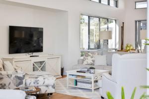 a living room with white furniture and a flat screen tv at Hampton Beach House on the Waterfront in Buddina +22 photos
