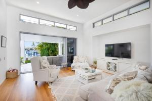 a living room with white furniture and a large window at Hampton Beach House on the Waterfront in Buddina
