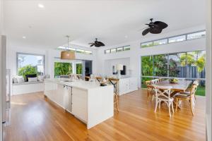 a kitchen and dining room with white cabinets and a table at Hampton Beach House on the Waterfront in Buddina