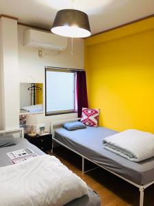 a room with two beds and a yellow wall at Guesthouse LuLuLu 無料朝食&夕食ｶﾚｰ付き ﾛｰｿﾝ隣 街まで電車8分 in Kochi