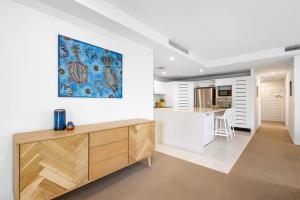 a kitchen with white walls and a painting on the wall at Peregian on the Beach Apt 1 in Peregian Beach +14 photos