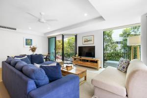 a living room with two blue couches and a tv at Peregian on the Beach Apt 1 in Peregian Beach