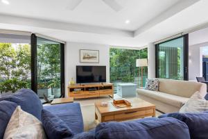a living room with two blue couches and a tv at Peregian on the Beach Apt 1 in Peregian Beach