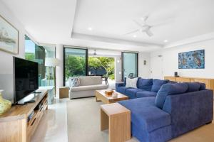a living room with a blue couch and a tv at Peregian on the Beach Apt 1 in Peregian Beach