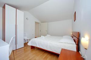 a bedroom with a white bed and a wooden floor at Apartments Andreja in Pag