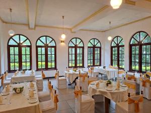 a banquet hall with white tables and chairs and windows at Royal Mount Hotel in Pussellawa