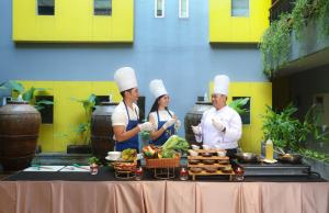 a group of chefs standing next to a table with food at Sevn Legian in Legian