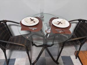 a glass table with two chairs and plates on it at Recanto dos Querubins in Cambé