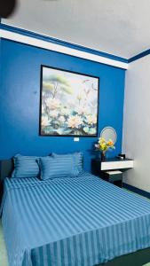 a blue bedroom with a bed and a painting on the wall at Favos Bích Động in Vũ Lâm
