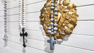 a rosary hanging on a wall with a cross at Le Petit Chateau in Medlow Bath
